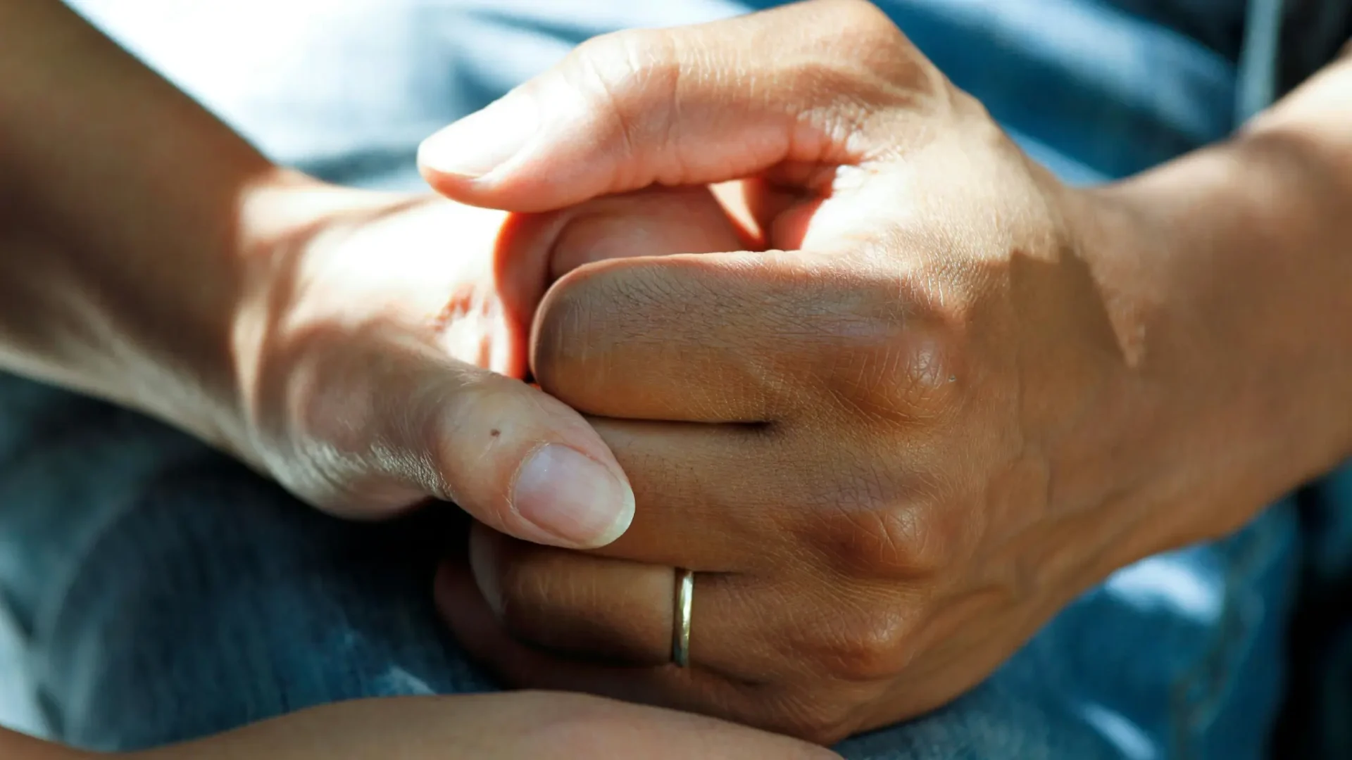 Two people holding hands in comfort and support during mesothelioma cancer recovery