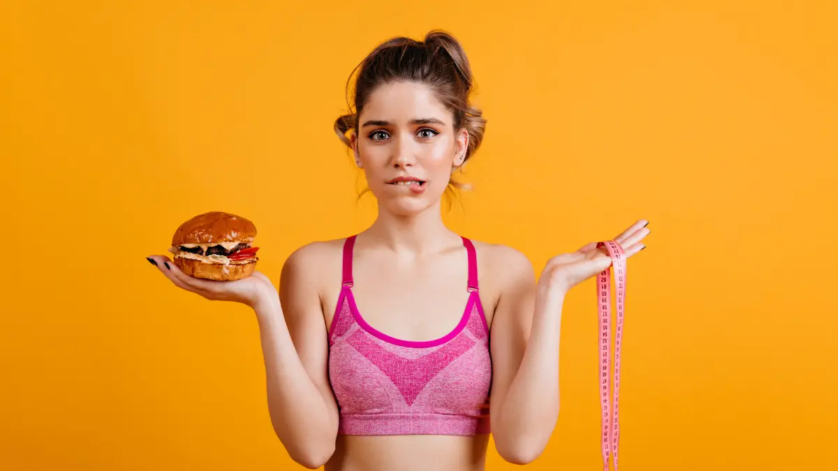 Person using a calorie deficit calculator on a tablet with healthy food and measuring tape in the background