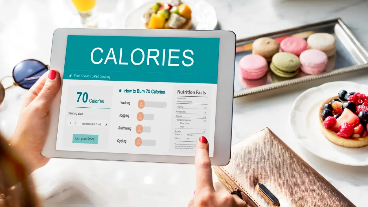 Woman using a digital calorie tracker on a tablet to understand BMR and daily energy needs