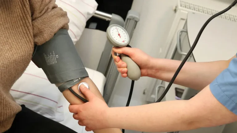 Healthcare professional measuring a patient’s blood pressure with a manual arm cuff and sphygmomanometer