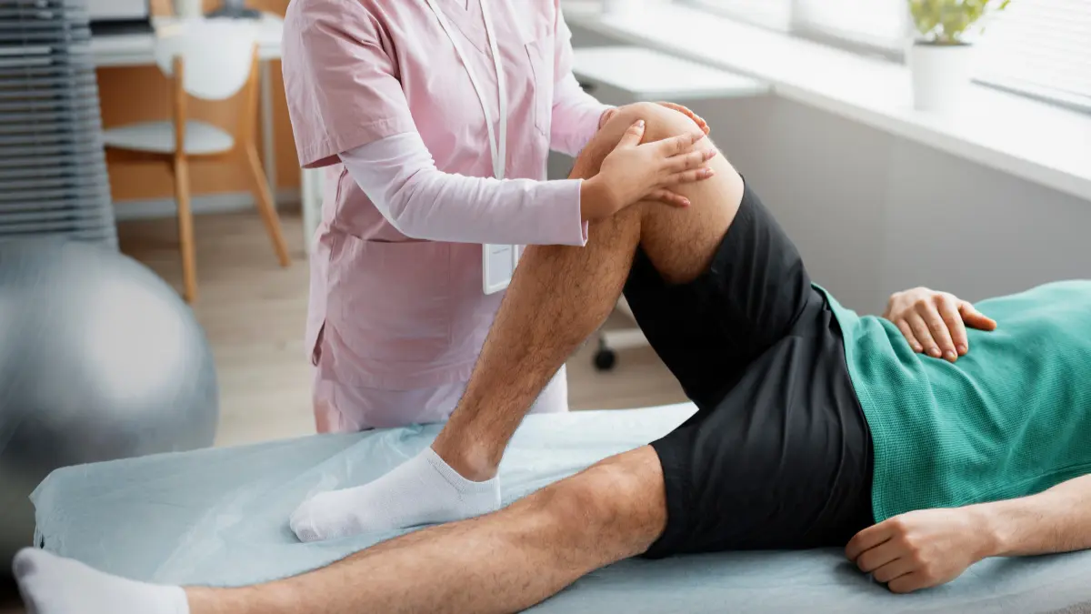 Physiotherapist supporting a patient’s knee during ACL tear recovery and rehabilitation exercises