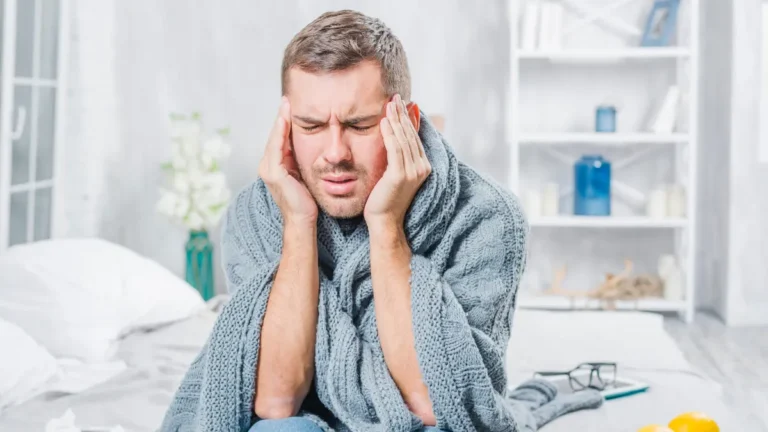 Man experiencing severe post-Christmas headache and holiday burnout wrapped in blanket showing exhaustion in 2025