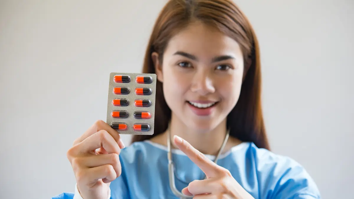Clinician holding a blister pack of capsules and pointing to it.