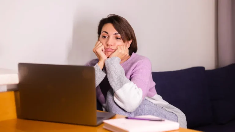 Woman experiencing chronic exhaustion and fatigue while working from home on laptop showing burnout symptoms