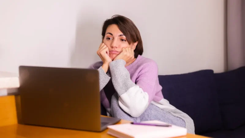 Woman experiencing chronic exhaustion and fatigue while working from home on laptop showing burnout symptoms