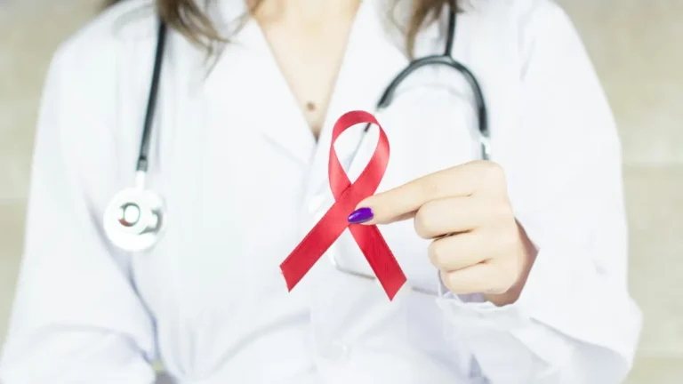 Doctor holding a red ribbon symbolizing HIV symptoms awareness