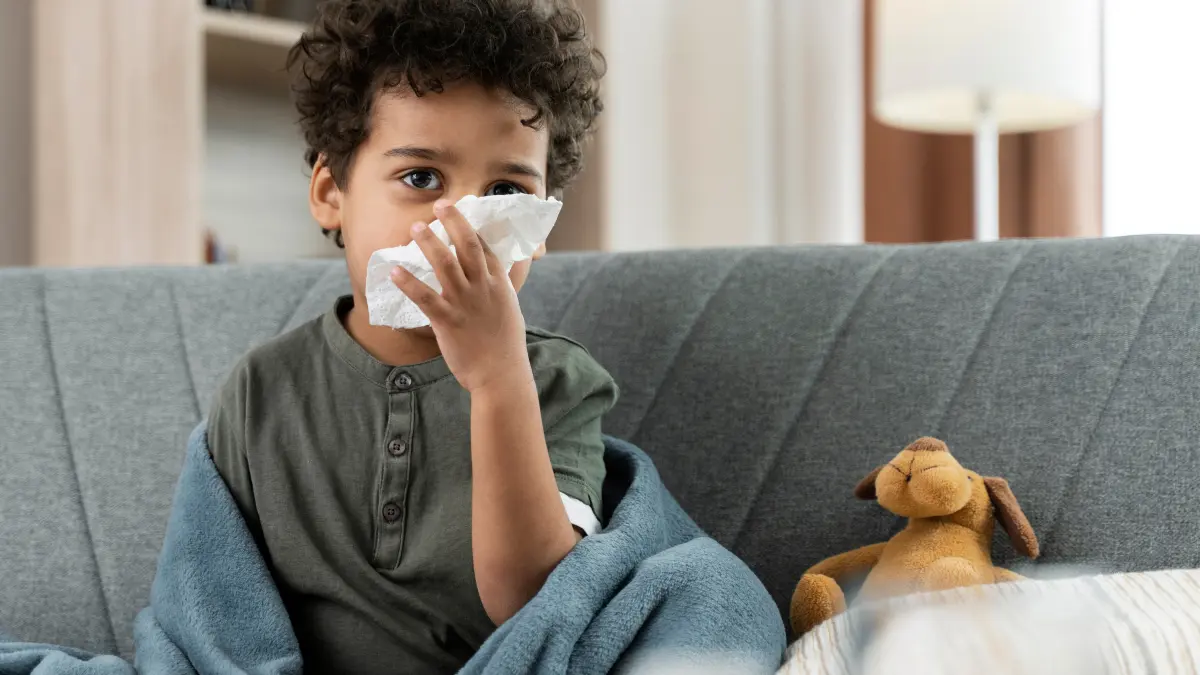 Flu in Kids showing a sick child with fever and runny nose resting at home