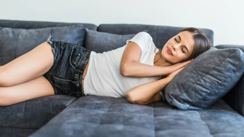 Woman resting on a couch with eyes closed, taking a quiet break.