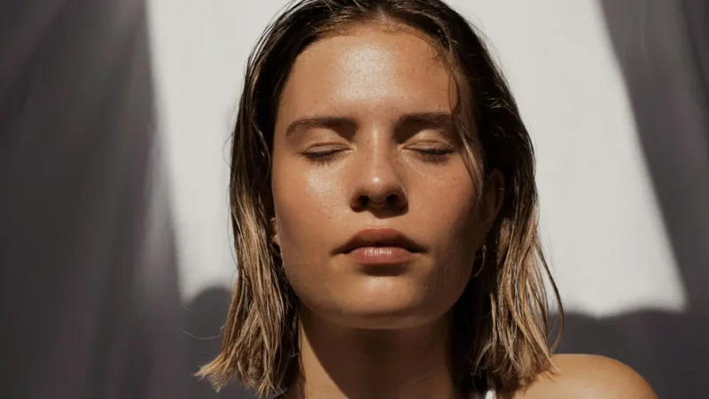 Woman with closed eyes in sunlight illustrating natural vitamin D production on skin