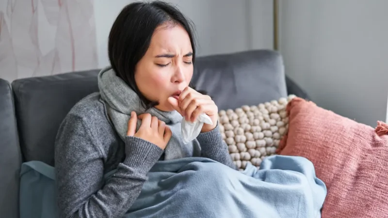 Woman feeling unwell with tissue on couch after Christmas experiencing post-holiday immune system crash