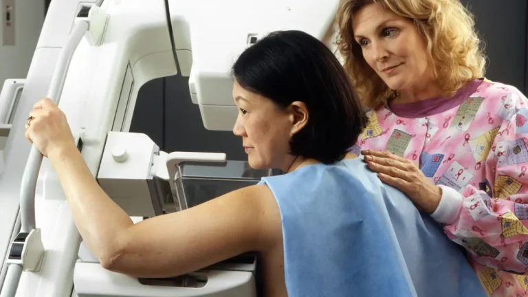 breast cancer screening mammogram procedure with technician positioning a woman at the imaging machine
