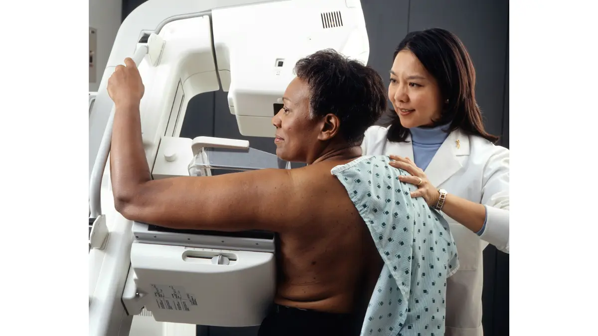 Breast cancer in Black women — mammogram screening procedure showing a female radiology technician performing breast cancer screening on an African-American woman patient.