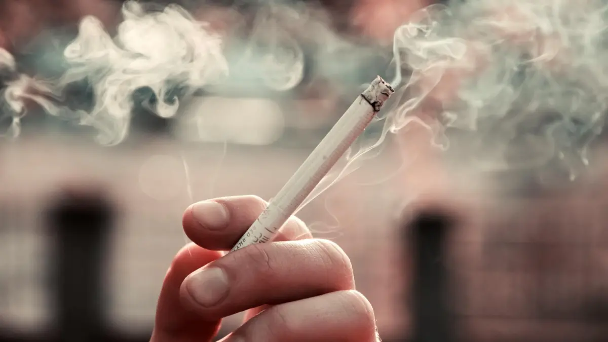 Close-up of a person holding a lit cigarette — quitting smoking is the single most effective action to prevent lung cancer at any age regardless of how many years a person has smoked