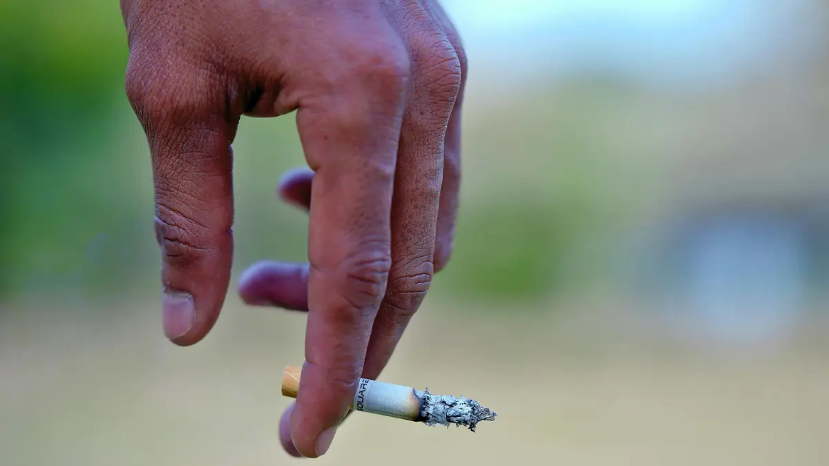 quit smoking lung cancer — cigarette in hand showing tobacco nicotine health hazard risk during chemotherapy cancer treatment