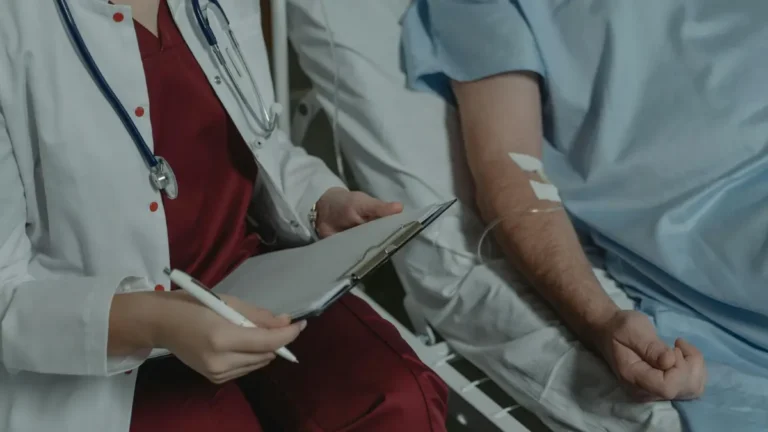 quit smoking lung cancer — oncologist consulting with cancer patient in hospital bed with IV drip during active treatment