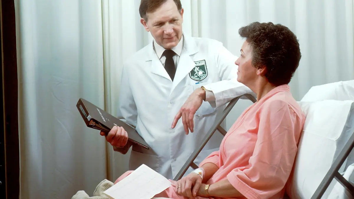 quit smoking lung cancer — board certified oncologist in white coat reviewing patient data tablet providing expert cessation guidance