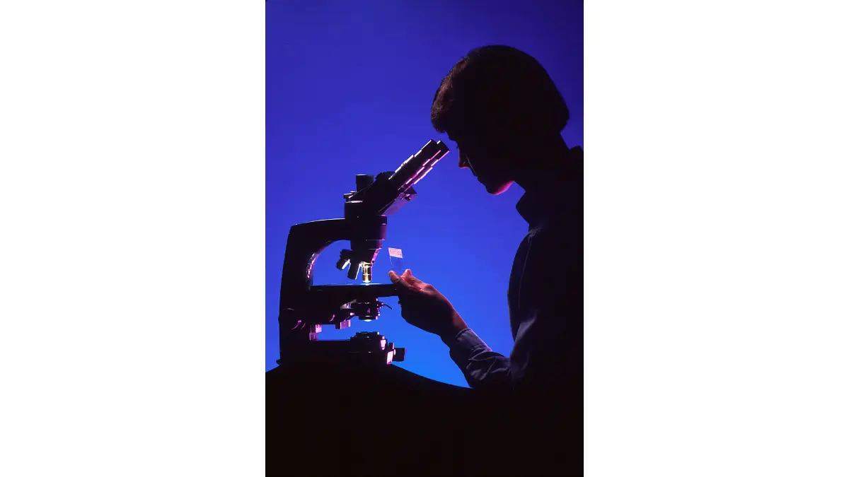 Colonoscopy pathology report image of a pathologist reviewing a tissue slide under a microscope.