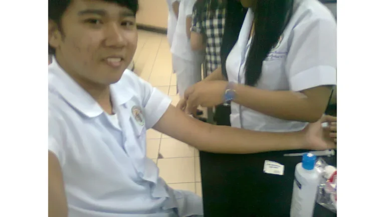 A medical student inserting a purple-top collection tube into a needle hub assembly during a patient CBC Test procedure.