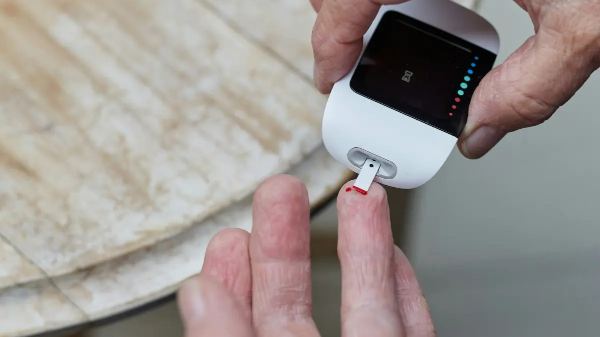 Close up photography of a patient preparing a blood glucose test strip to verify if a CMP detect diabetes risk profiles.