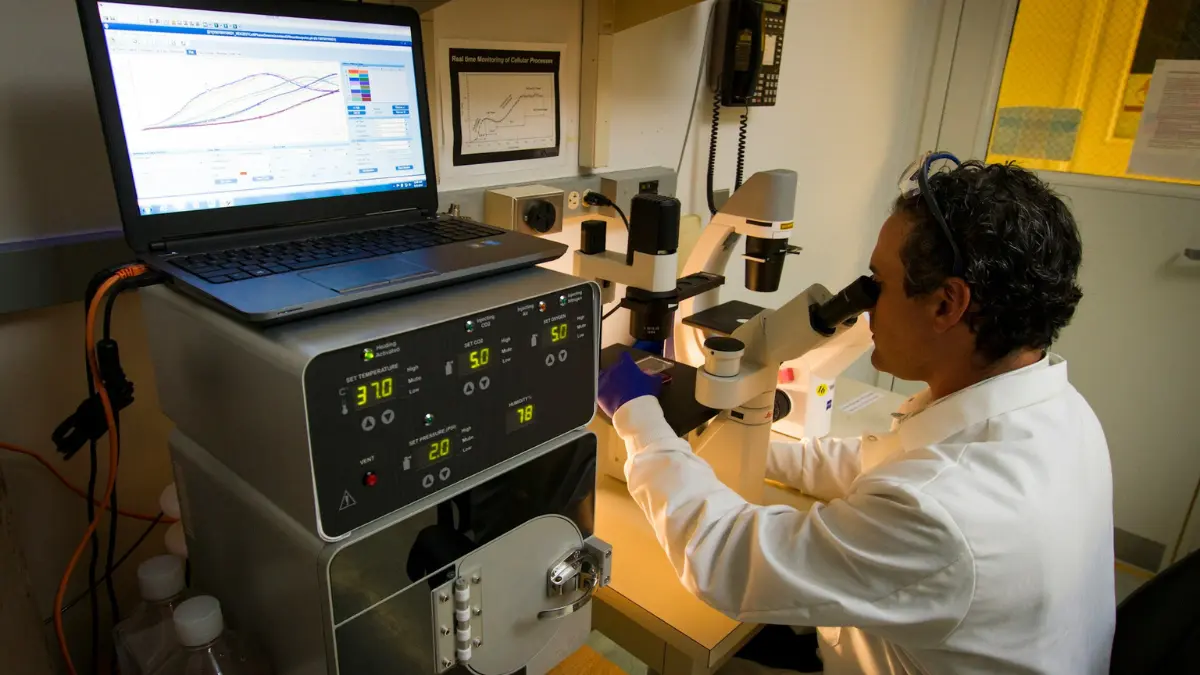 A laboratory professional checking cellular details under a microscope to confirm if a CMP detect cancer.