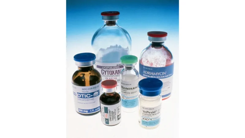 A variety of oncology prescription medicine vials resting over a blue gradient background, illustrating multi-drug plans affecting pancreatic cancer treatment cost.
